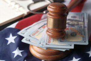 A wooden gavel on stacks of cash with US flag in the background, symbolizing court-awarded attorney fees.