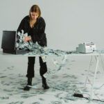 Person handling large stacks of cash spilling out of a briefcase, symbolizing financial management and potential debt restructuring fraud.