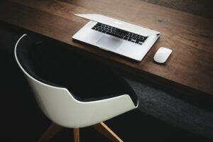Minimalist workspace with a partially closed laptop on a wooden desk, symbolizing strategic planning and legal approaches to address client payment delays in staffing firms.
