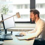 A business professional working at a desk, smiling, representing effective financial controls and collection strategies to safeguard staffing firms from accumulating bad debt.