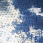 Reflection of clouds on a glass building, representing strategic receivables management for B2B SaaS companies aiming to scale smartly while maintaining financial health.