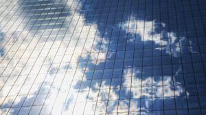 Reflection of clouds on a glass building, representing strategic receivables management for B2B SaaS companies aiming to scale smartly while maintaining financial health.