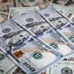 Close-up of scattered U.S. paper currency, with crisp $100 bills layered over older, worn banknotes, symbolizing business debt recovery or financial claims.