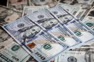 Close-up of scattered U.S. paper currency, with crisp $100 bills layered over older, worn banknotes, symbolizing business debt recovery or financial claims.