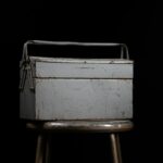 Worn metal toolbox on a stool in a dark setting, symbolizing the legal tools and strategies used in judgment enforcement.