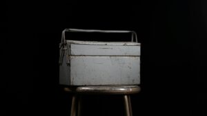 Worn metal toolbox on a stool in a dark setting, symbolizing the legal tools and strategies used in judgment enforcement.