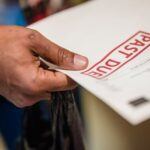 Close-up of a person holding a letter marked "Past Due," symbolizing unpaid debts or overdue financial obligations.