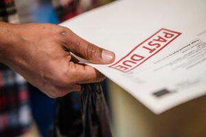 Close-up of a person holding a letter marked "Past Due," symbolizing unpaid debts or overdue financial obligations.