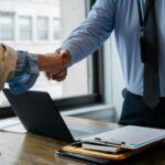 Businessperson and attorney shaking hands over desk with legal paperwork, symbolizing agreement and asset turnover in California judgment enforcement cases
