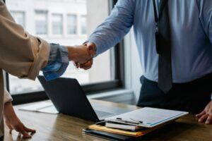 Businessperson and attorney shaking hands over desk with legal paperwork, symbolizing agreement and asset turnover in California judgment enforcement cases