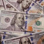 A close-up view of several overlapping $100 bills, representing funds at stake in bank levy enforcement and the importance of avoiding procedural errors in judgment collections